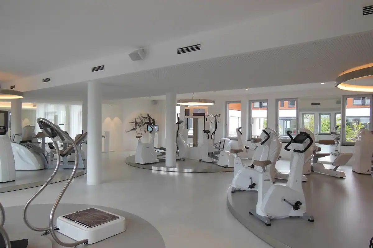Sală spațioasă cu biciclete staționare și aparate cardio aliniate lângă ferestre mari