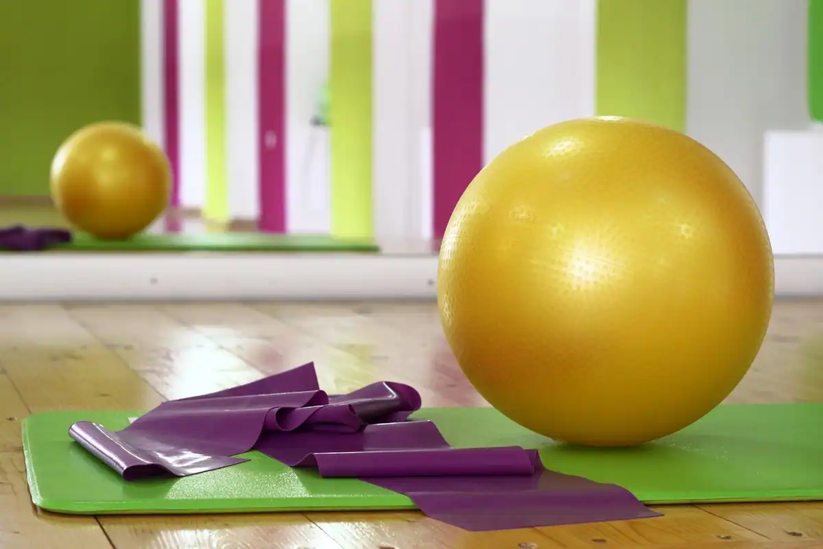 Benzi elastice violet, o minge galbenă și o saltea verde pregătite pentru exerciții