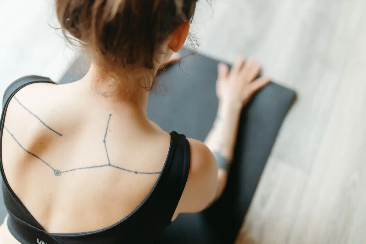 Femeie văzută din spate, într-o poziție de yoga care întinde coloana toracică