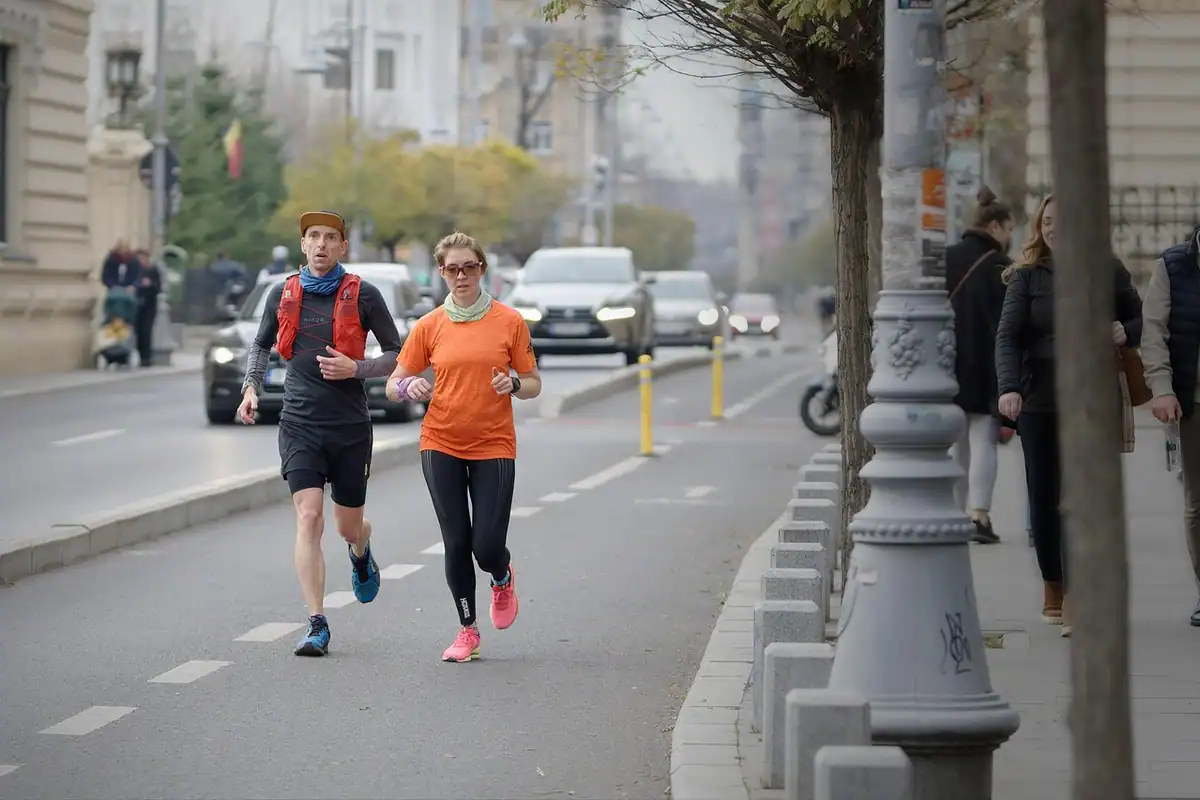 Doi alergători aleargă pe lângă o stradă, în ritm care permite conversația